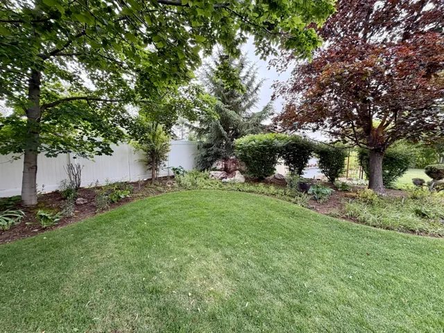 Expansive lawn area bordered by a white privacy fence