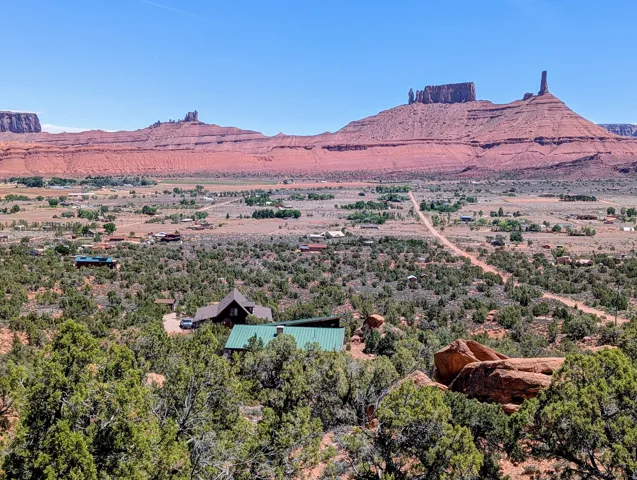 Property featuring a prominent green roof, surrounded by native trees and desert foliage