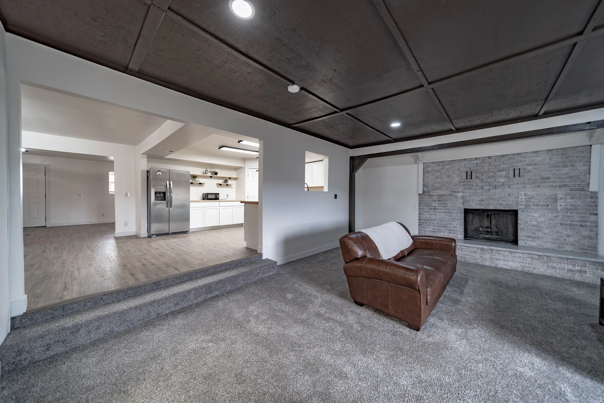 Spacious living area featuring a coffered ceiling, a brick fireplace, and recessed lighting