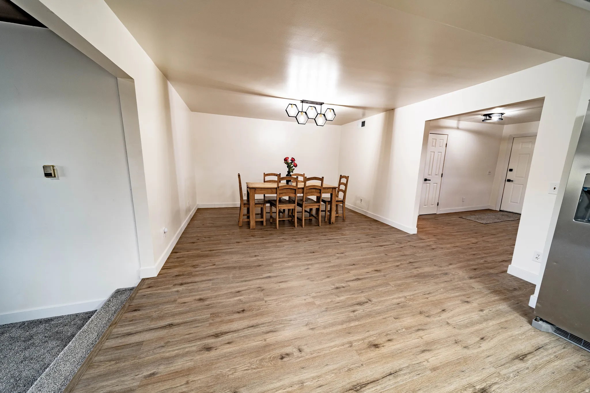 Open-concept room featuring wood-finish flooring, white walls, and a contemporary ceiling fixture