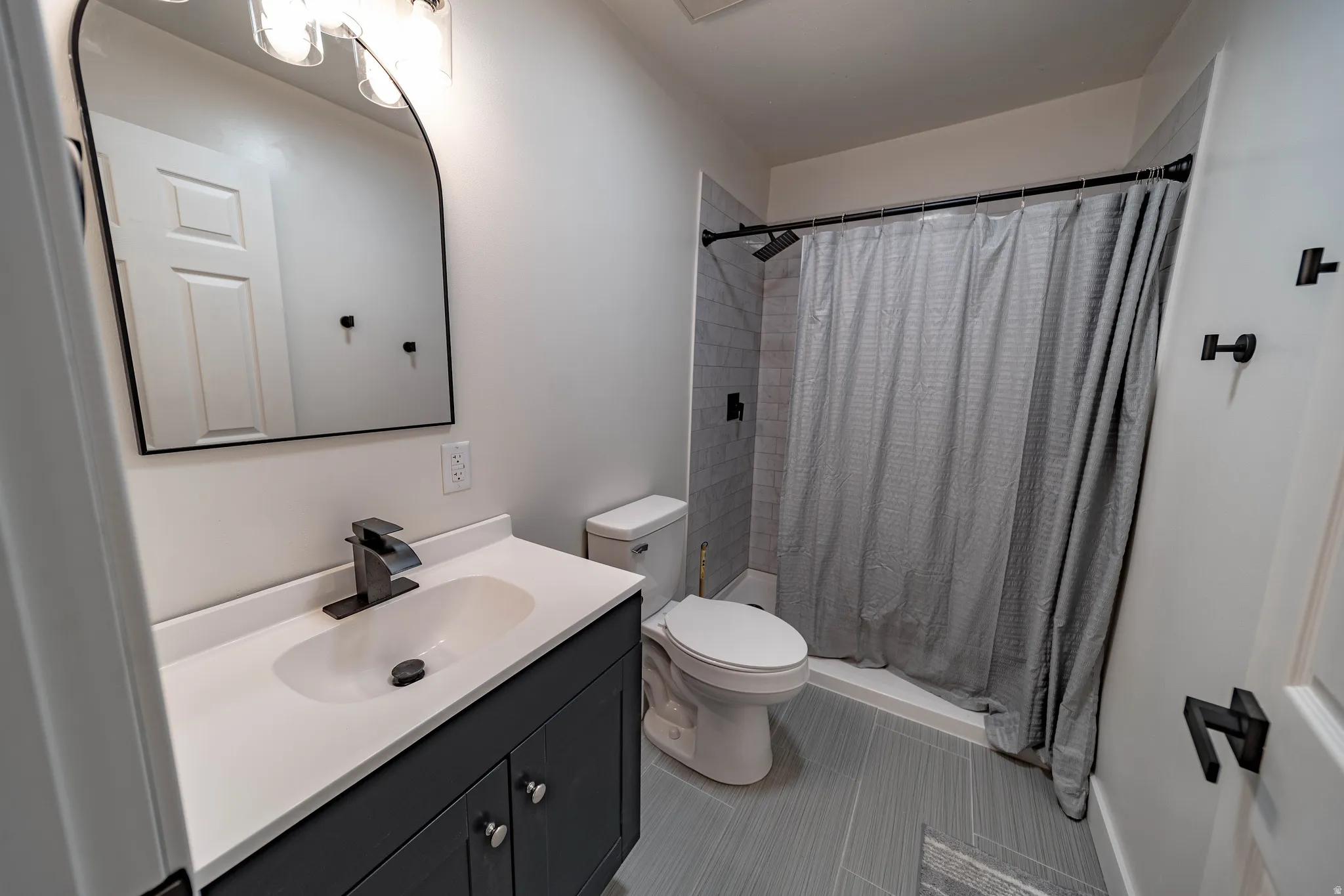 Full bathroom with a dark gray vanity, white countertop, and integrated sink
