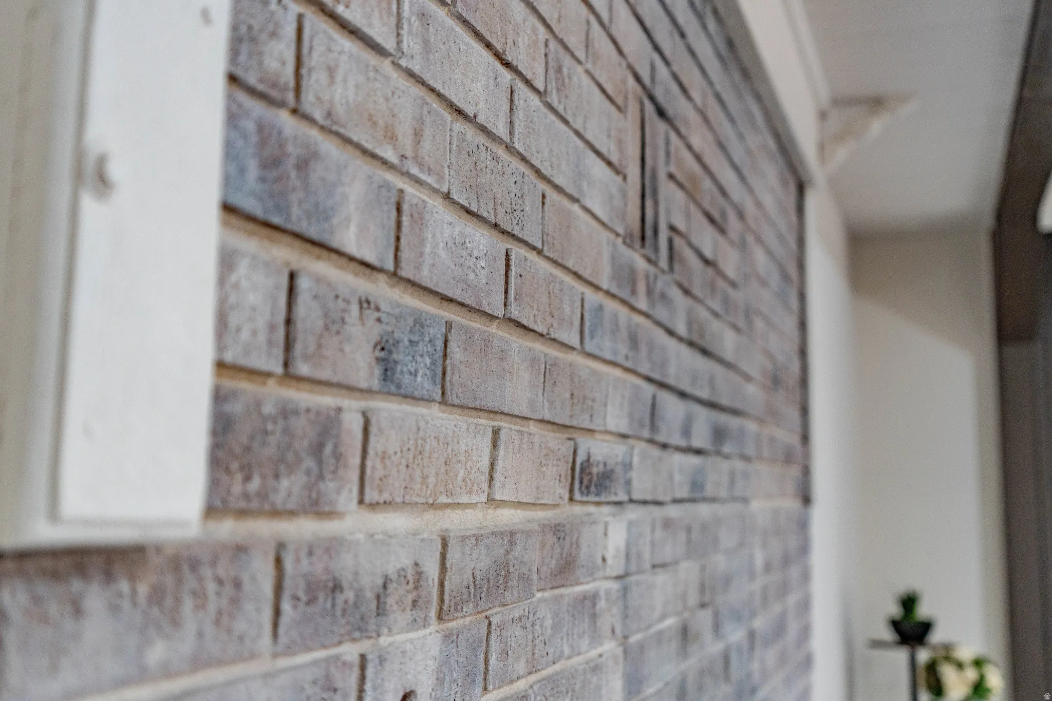 Decorative brick wall with varied gray and brown tones, featuring a prominent vertical white architectural trim piece