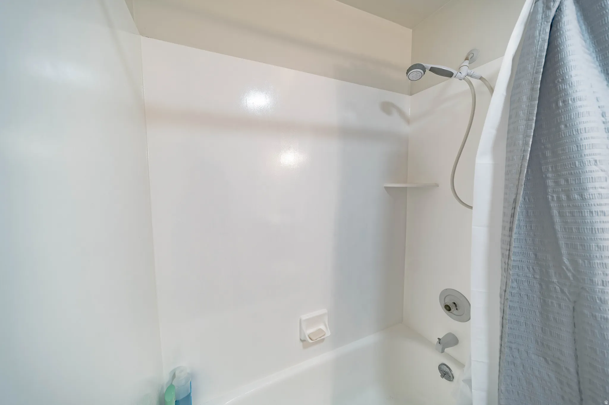 White fiberglass tub and shower combination with an integrated soap dish and shelf