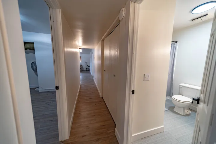 Hallway featuring wood-finish flooring, white painted walls, and built-in closet doors