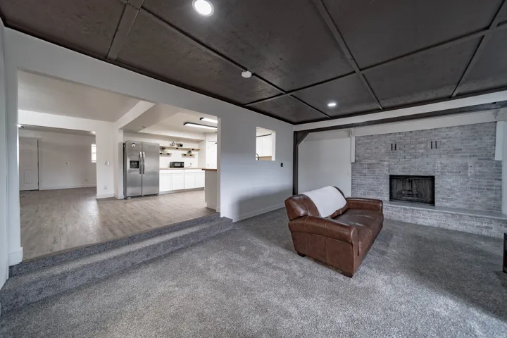 Spacious living area featuring a coffered ceiling, a brick fireplace, and recessed lighting