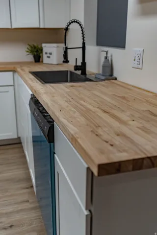 Wood-finish countertops with an undermount sink and black gooseneck faucet
