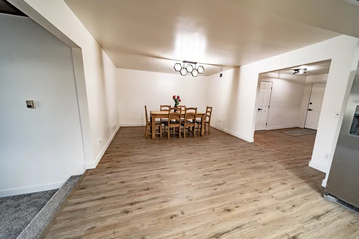 Open-concept room featuring wood-finish flooring, white walls, and a contemporary ceiling fixture