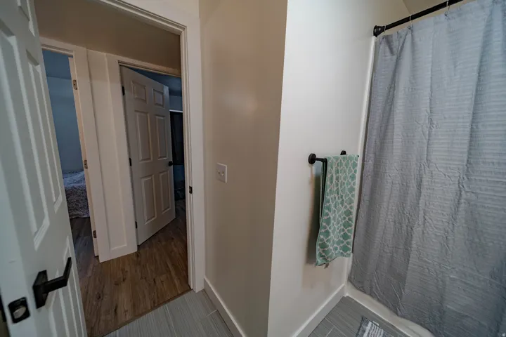 Shower enclosure with horizontal tile flooring and a black shower rod