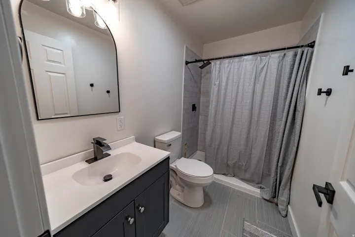 Full bathroom with a dark gray vanity, white countertop, and integrated sink