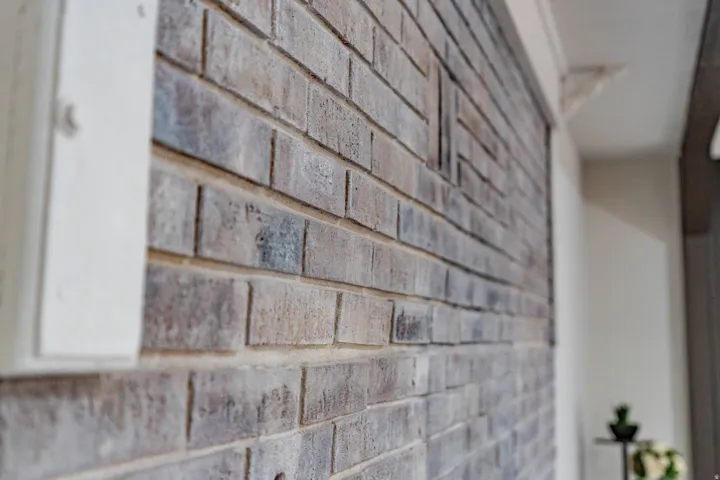 Decorative brick wall with varied gray and brown tones, featuring a prominent vertical white architectural trim piece