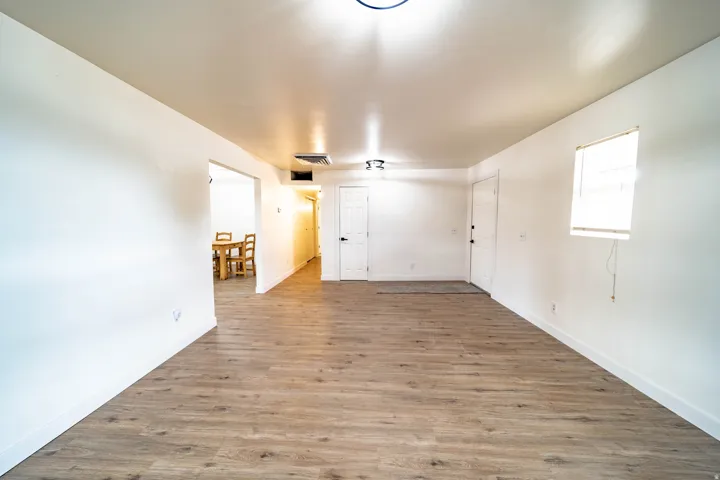 Spacious room featuring wood-finish flooring, white walls, and a white ceiling