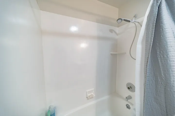 White fiberglass tub and shower combination with an integrated soap dish and shelf