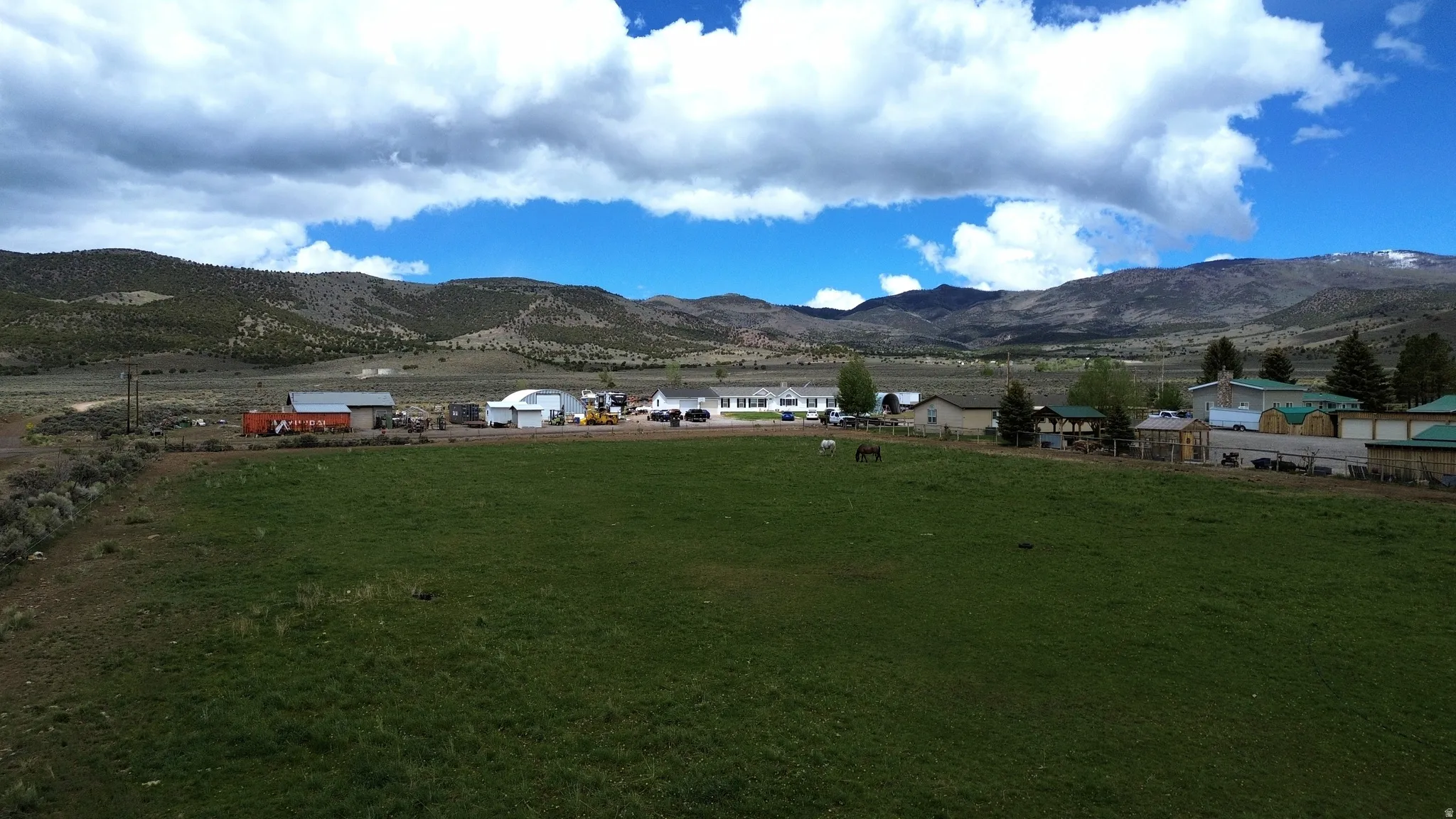 Expansive green field with natural landscaping, surrounded by distant mountains