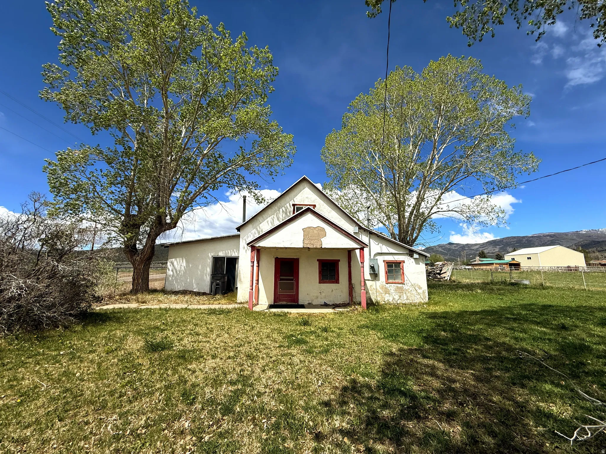 White stucco residence with a prominent red front door and a covered porch with red columns