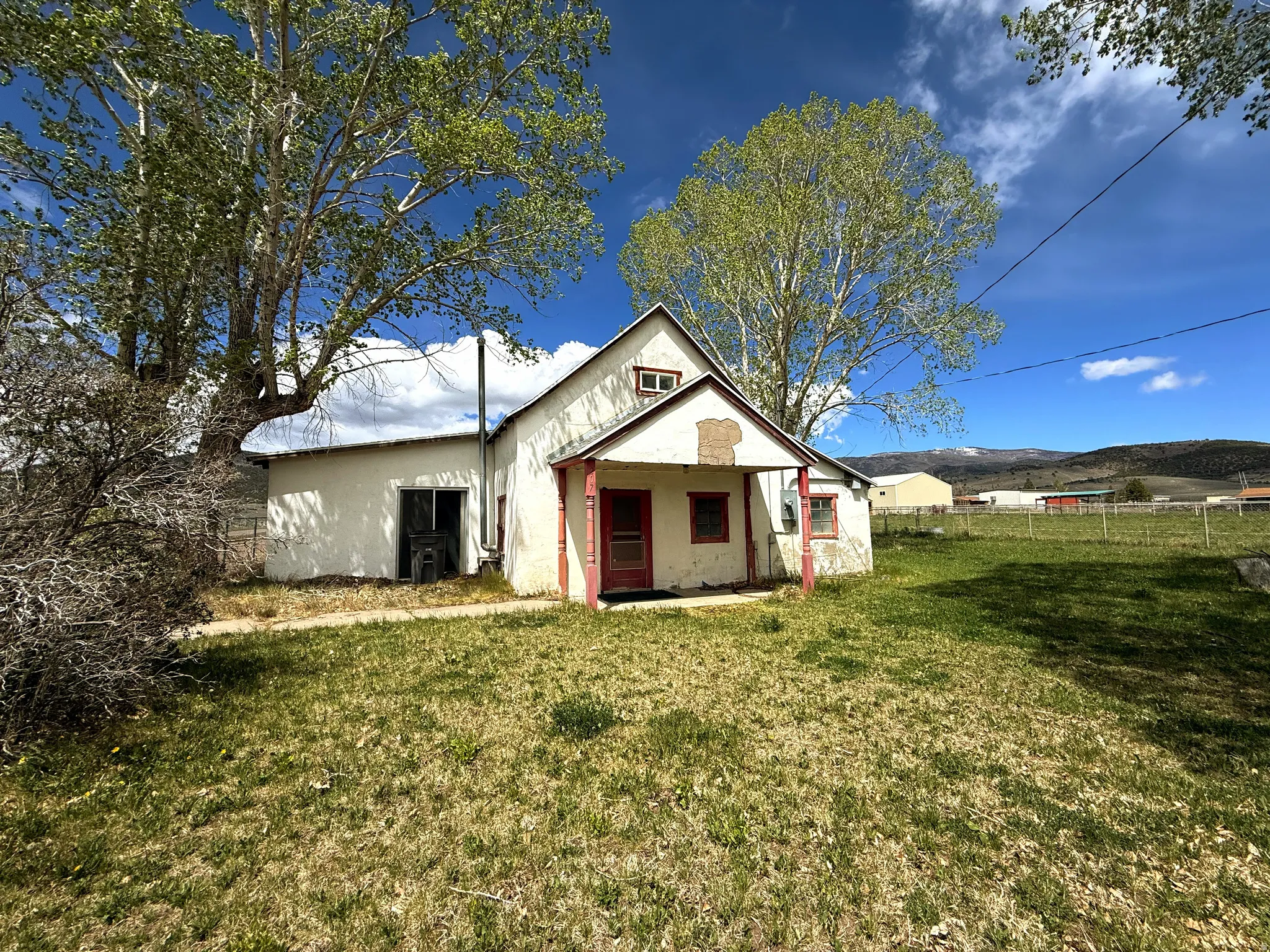 White stucco exterior featuring a red-trimmed front porch and multiple window openings