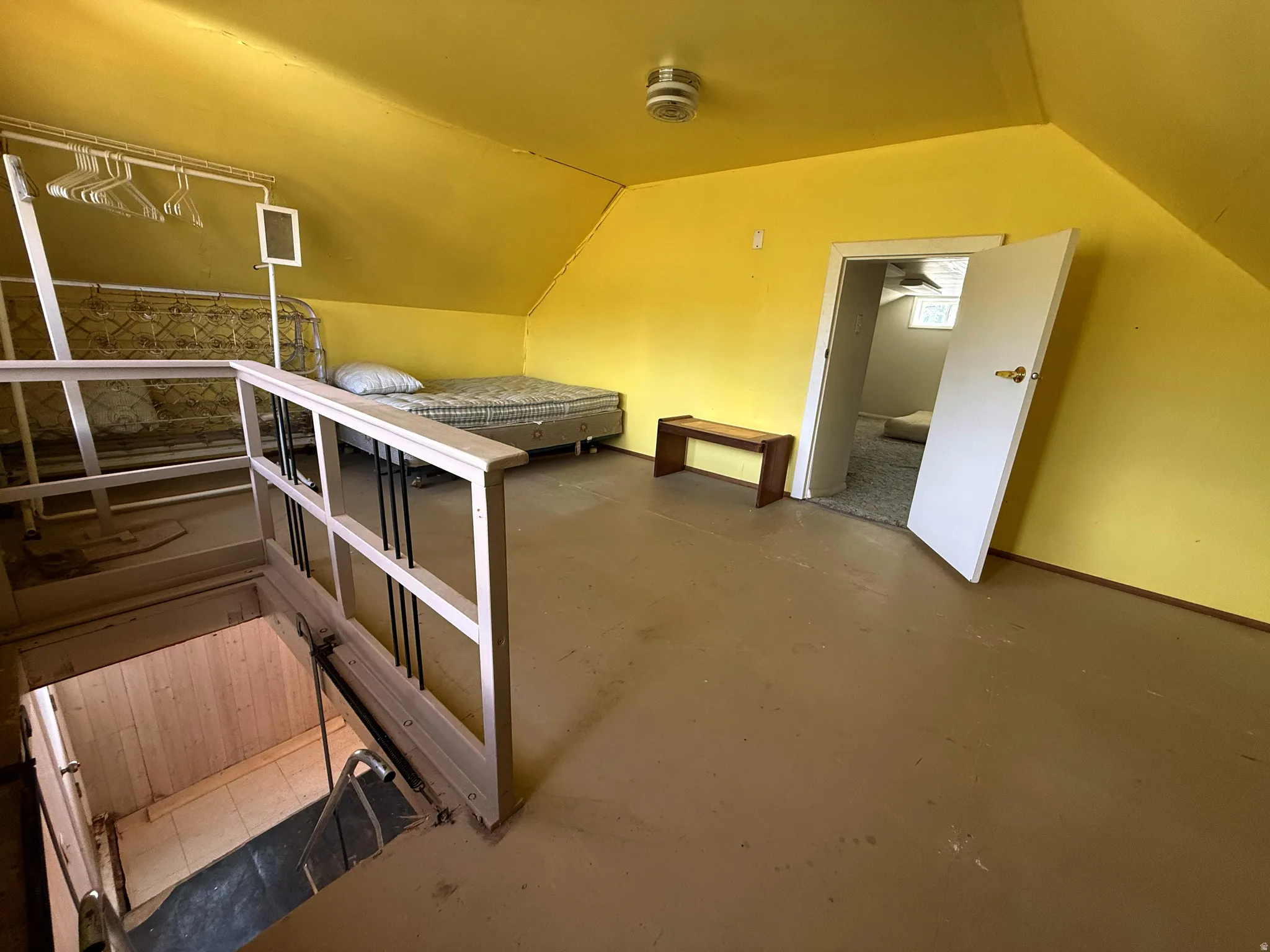 Attic room featuring sloped ceilings, painted walls, and a doorway opening to an additional space