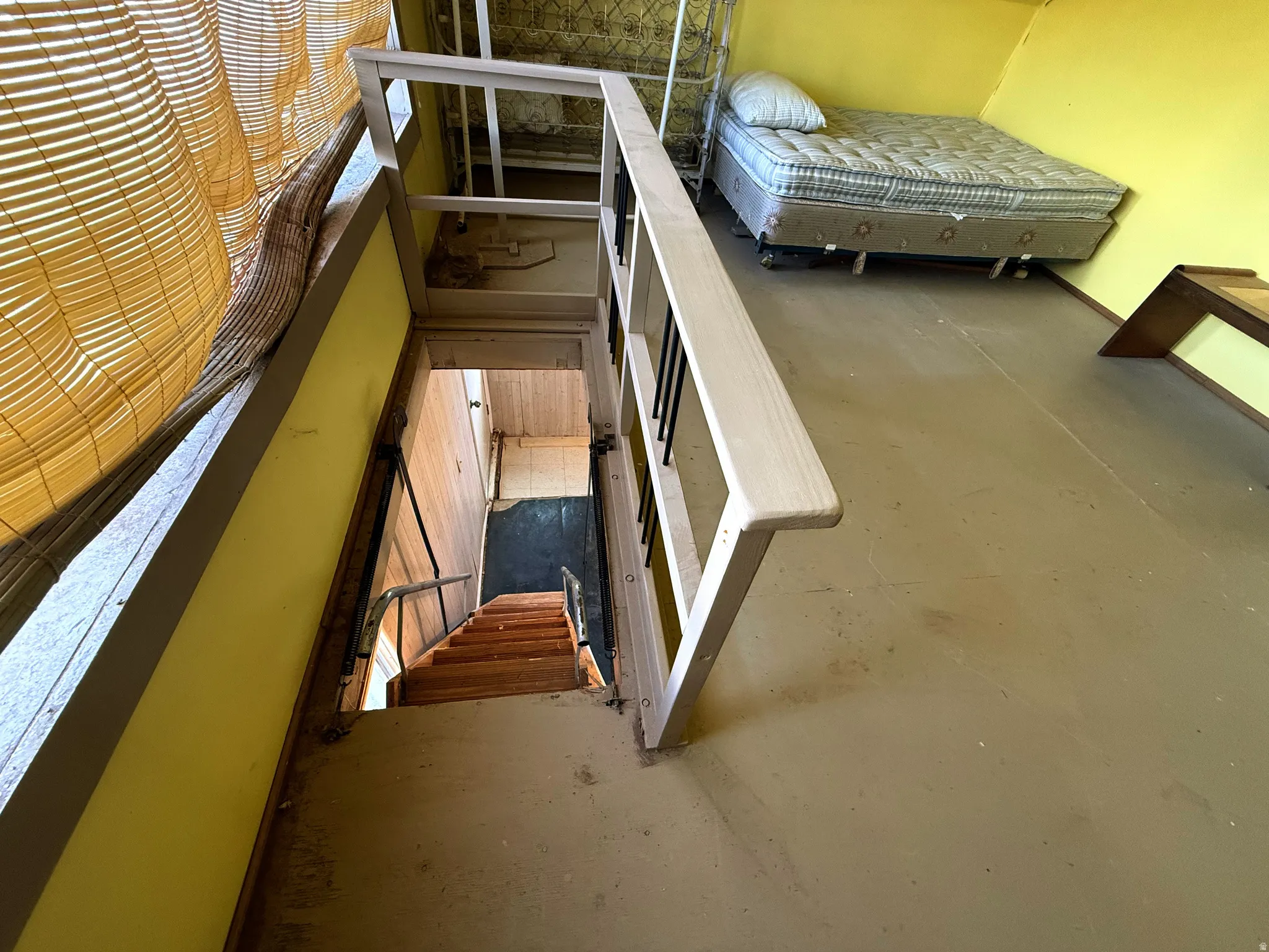 Stairwell with light wood banister, metal balusters, and wood-finish treads leading to a lower level