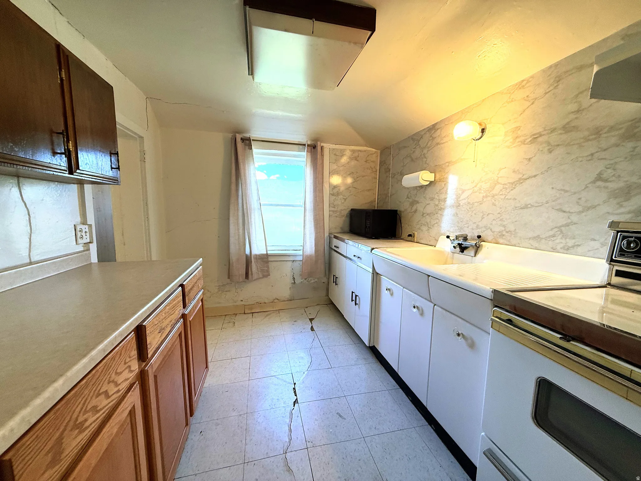 Kitchen featuring wood-finish lower cabinetry, a laminate countertop, and a double-basin sink