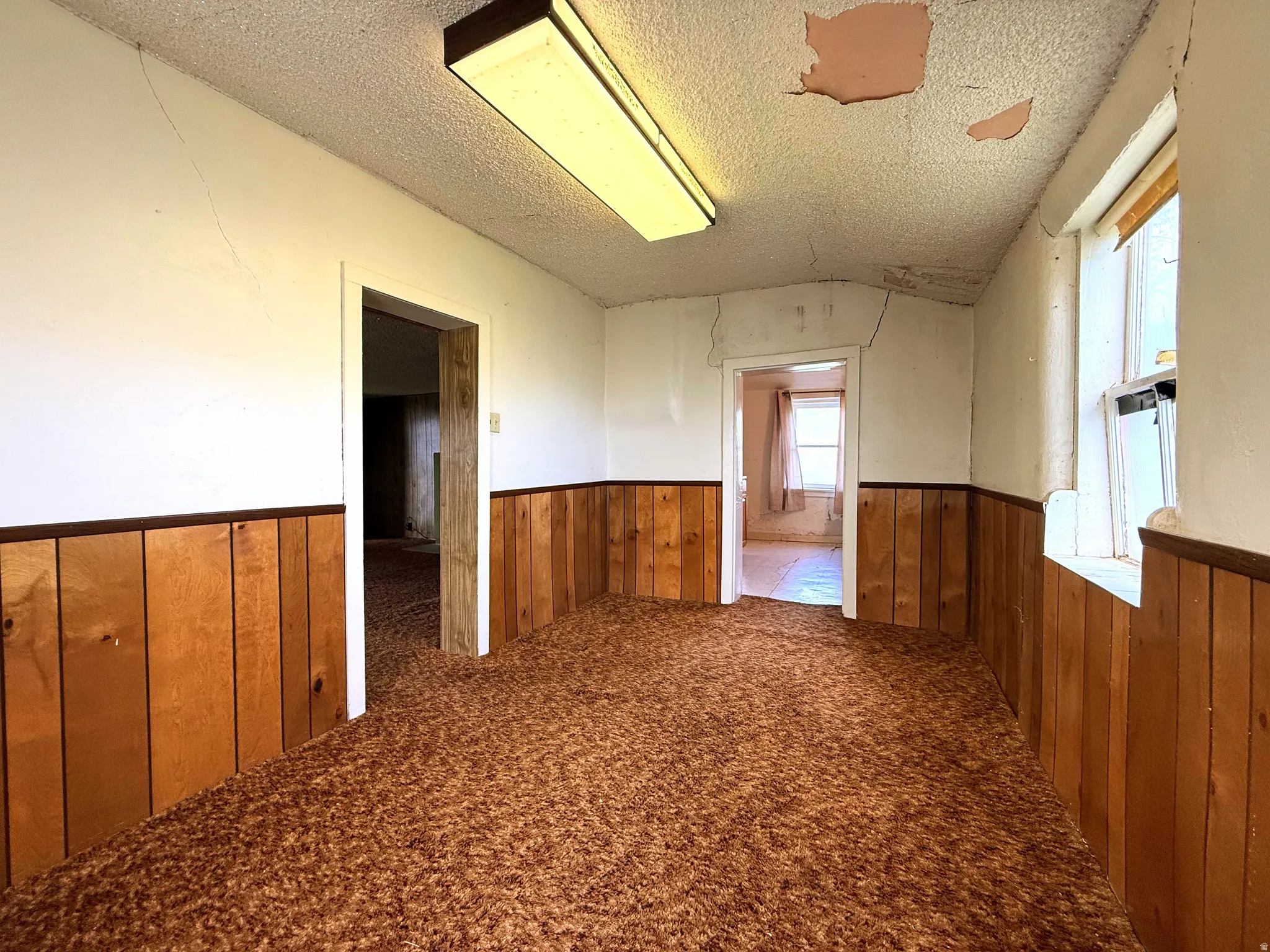 Interior room featuring wood-panel wainscoting and a textured ceiling