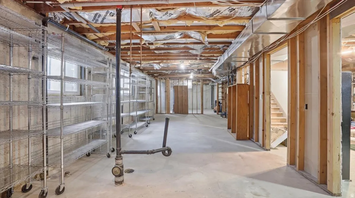 Expansive unfinished basement featuring concrete flooring, exposed ceiling joists, and framed partition walls