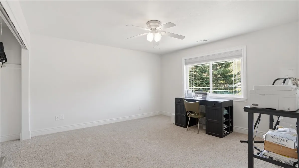 Carpeted room with white walls, a ceiling fan with integrated lighting, and a large window