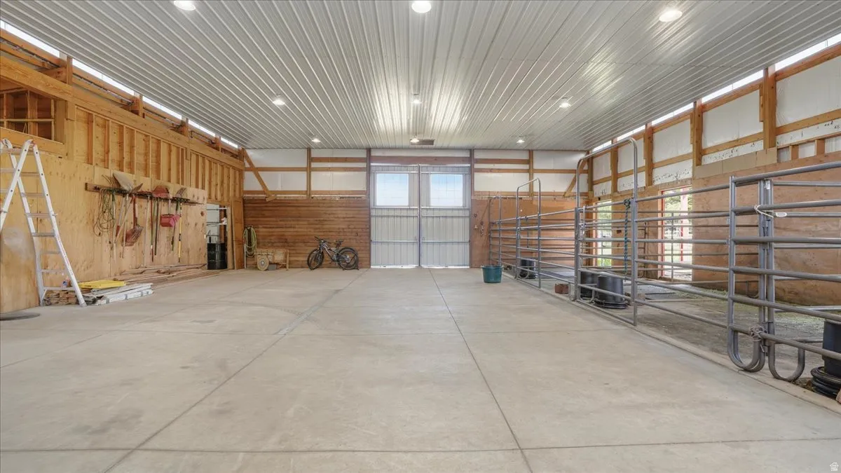 Spacious barn interior featuring concrete flooring, a corrugated metal ceiling with recessed lighting, and exposed wood framing