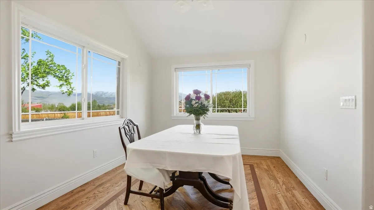 Bright room featuring two large windows with horizontal mullions, wood-finish flooring with a decorative inlay, clean white walls, and elegant baseboards