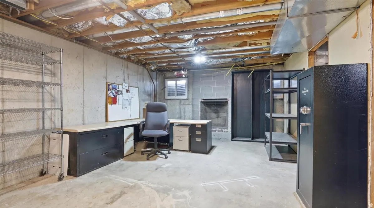Unfinished basement space with concrete flooring, exposed ceiling joists, and concrete block walls