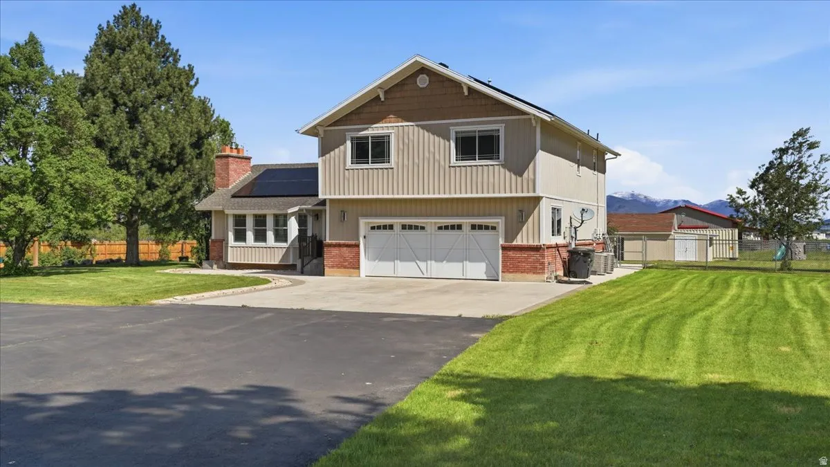 Two-story property featuring a white double garage door, brick accents, and vertical siding