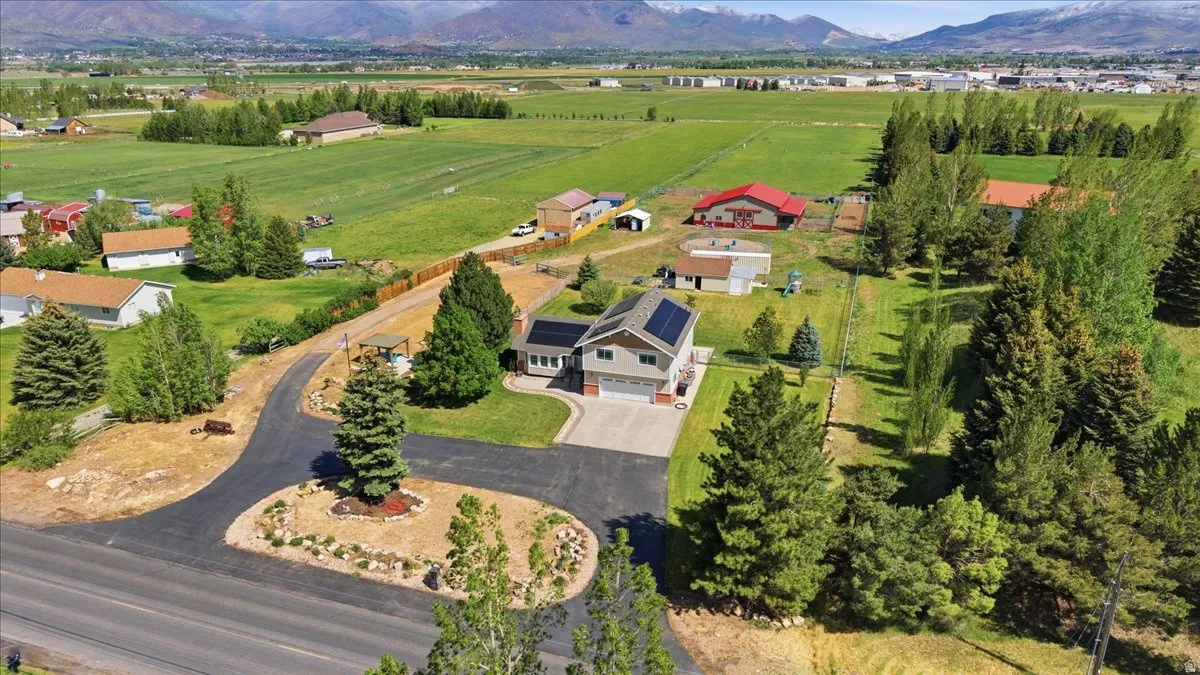 Two-story residence featuring an attached garage, solar panel installation, and a paved driveway with a central landscaped island