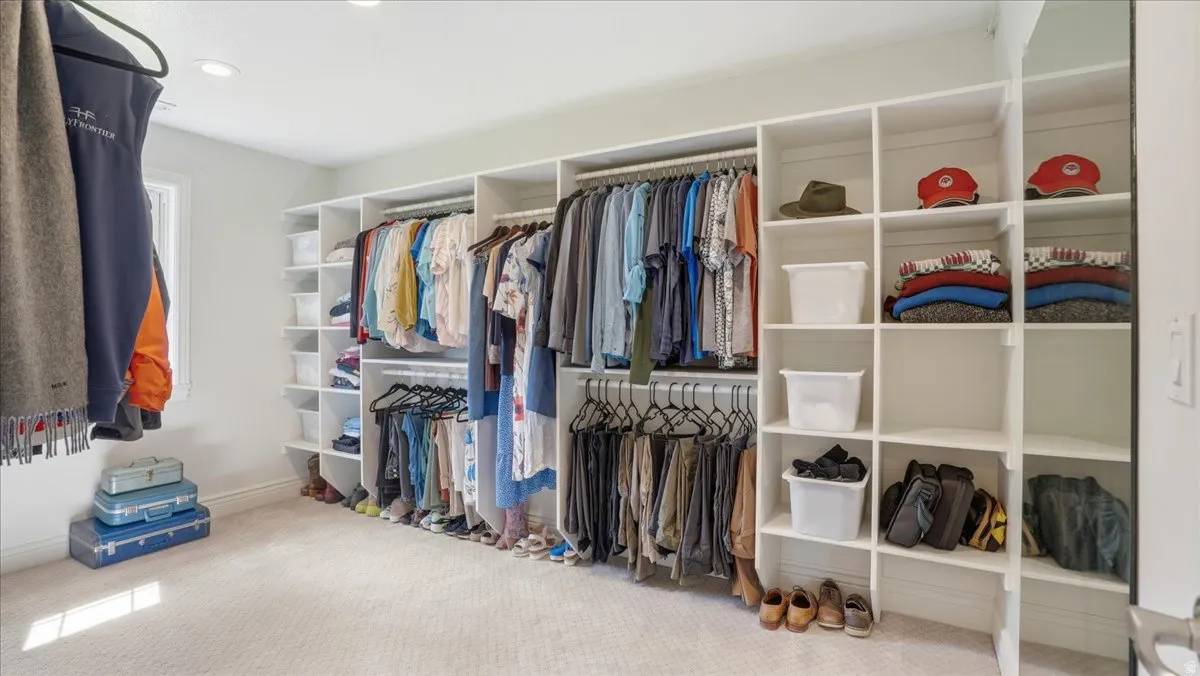 Custom closet organization system featuring white shelving, multiple hanging rods, built-in cubbies, and a full-length mirror