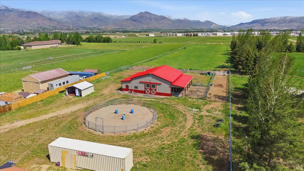 Expansive property featuring a red-roofed barn with red trim, a fenced round pen, and additional outbuildings