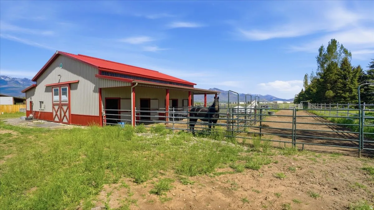 Barn structure featuring a red metal roof, light-colored siding, and red trim