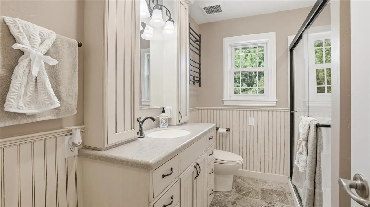 Bathroom featuring a single vanity with built-in storage, light-toned countertop, and undermount sink