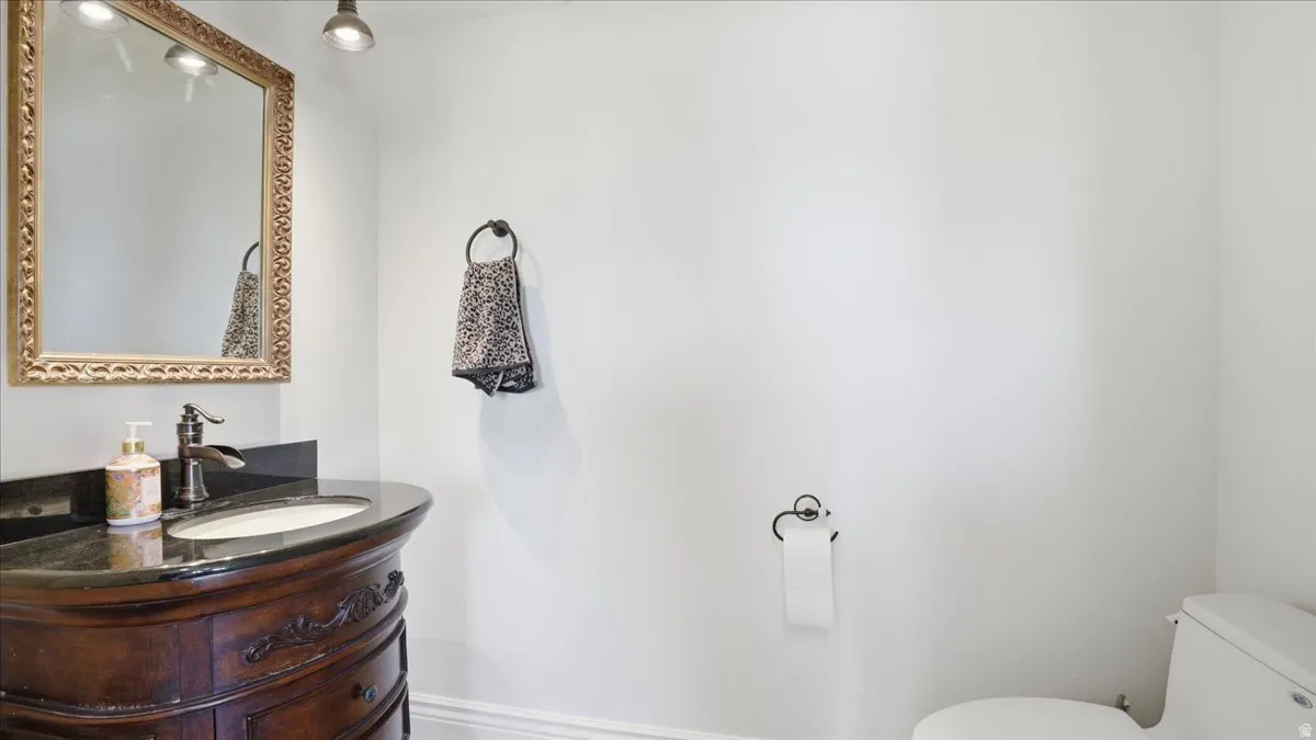 Ornate wooden vanity with a dark stone countertop, undermount sink, and bronze-finish faucet
