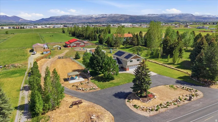 Expansive property featuring a contemporary residence with solar panels, a paved driveway, and established landscaping