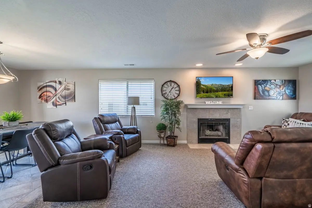 Living area featuring a stone-clad fireplace with a classic mantel, recessed lighting, and a ceiling fan