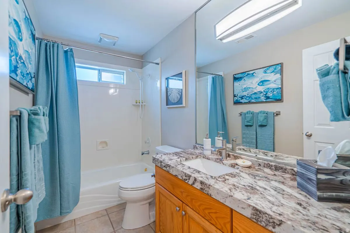 Bathroom featuring a vanity with a large mirror, a rectangular sink, and a stone-finish countertop