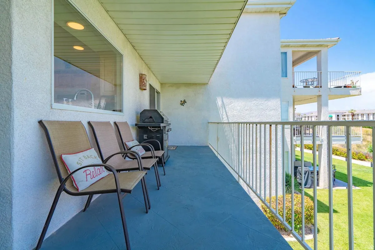 Spacious balcony featuring a painted concrete floor, white stucco exterior, and a white railing