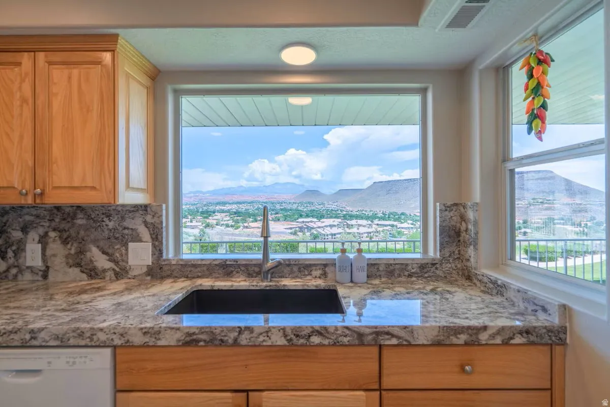 Kitchen sink with a contemporary faucet, integrated into a natural stone countertop featuring a full backsplash