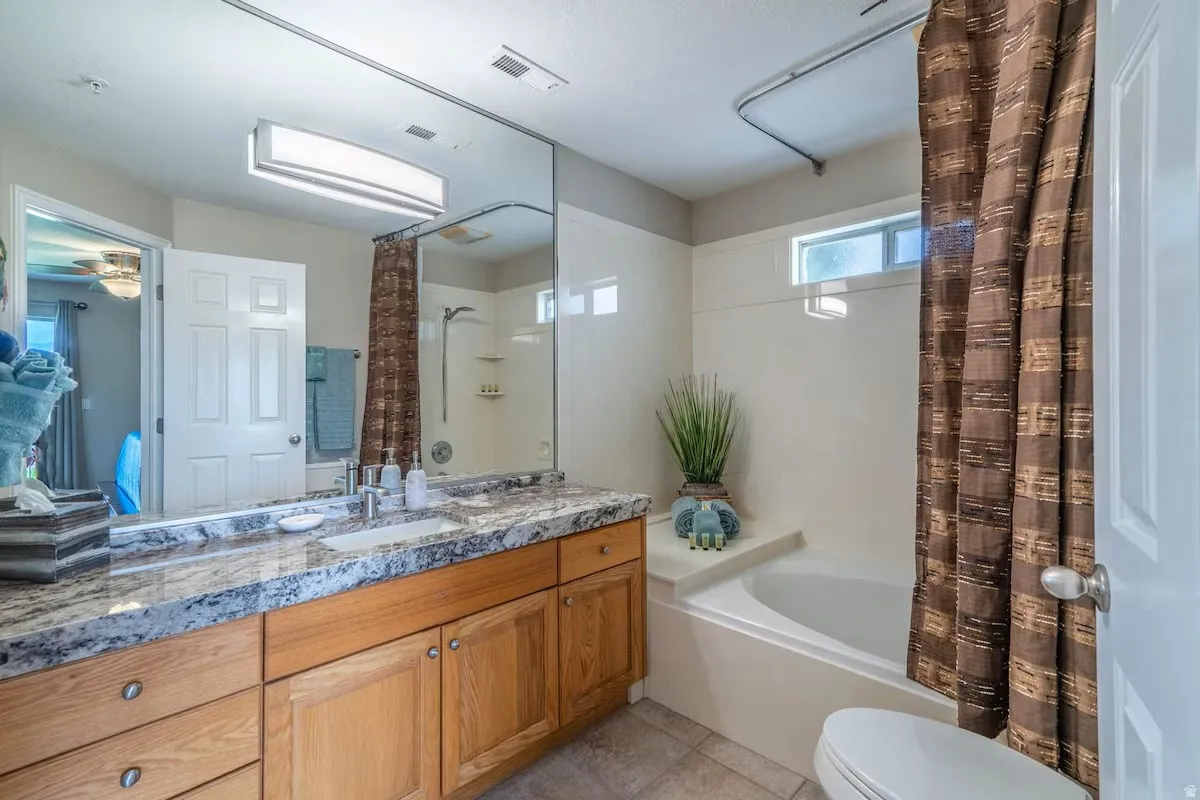 Bathroom featuring a spacious vanity with a light-toned stone countertop, an integrated sink, and wood-finish cabinetry
