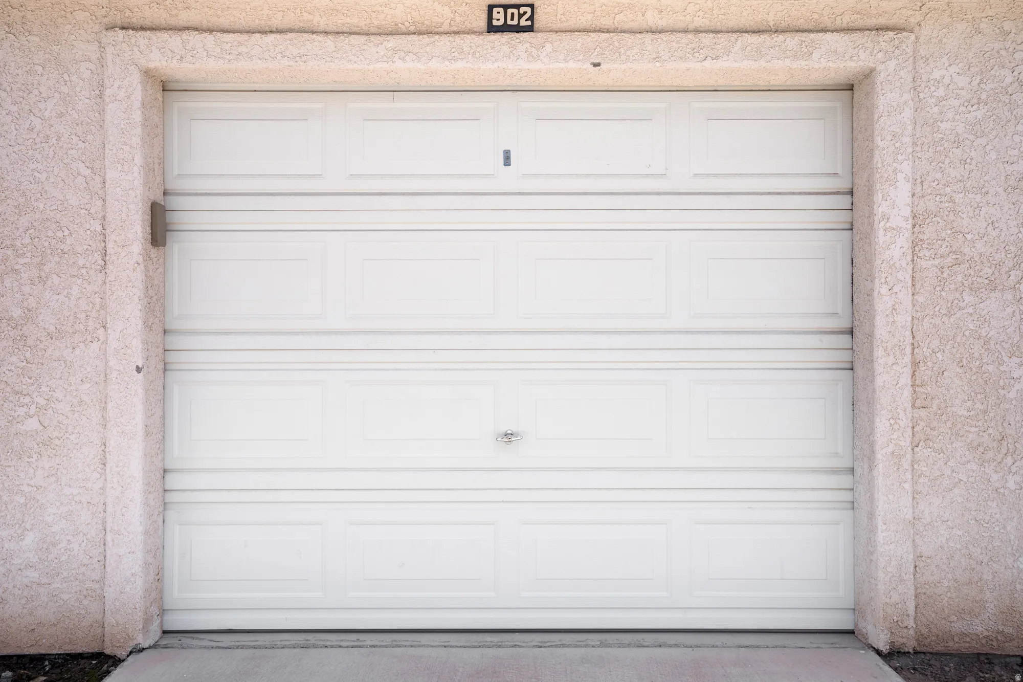 White paneled garage door framed by stucco exterior