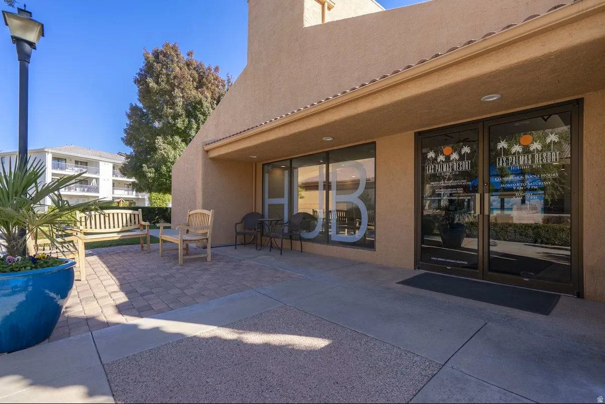 Exterior stucco building featuring an awning over the entrance, dual glass paneled doors, and large storefront windows