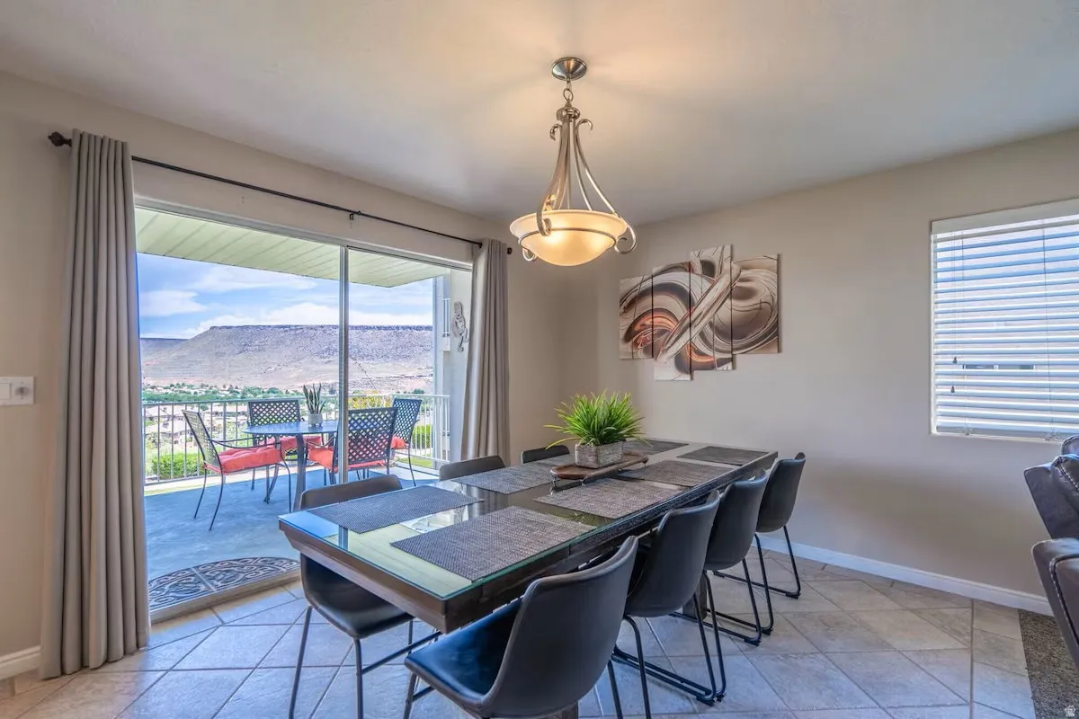 Spacious dining area featuring neutral wall tones, a contemporary chandelier, and tile flooring