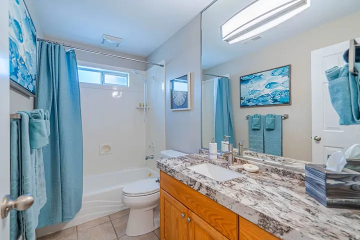 Bathroom featuring a vanity with a large mirror, a rectangular sink, and a stone-finish countertop