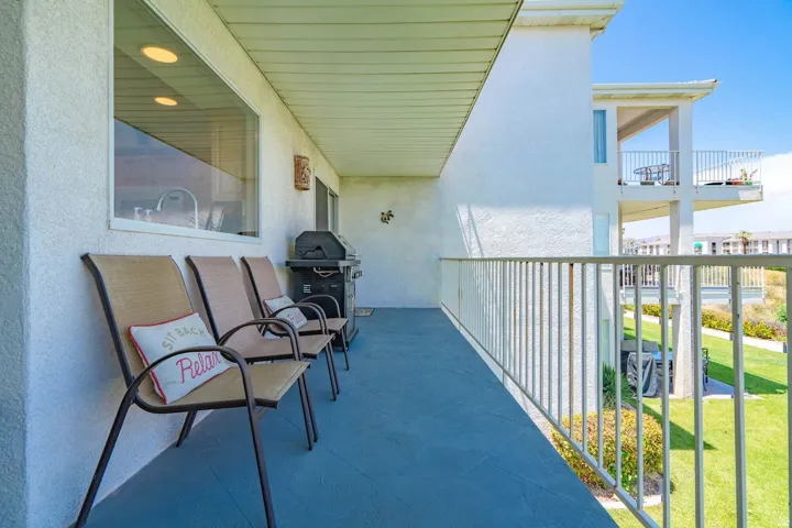Spacious balcony featuring a painted concrete floor, white stucco exterior, and a white railing
