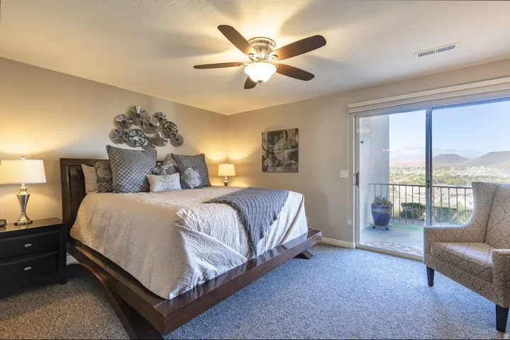 Bedroom featuring sliding glass door to exterior, carpeted flooring, and a ceiling fan with integrated lighting