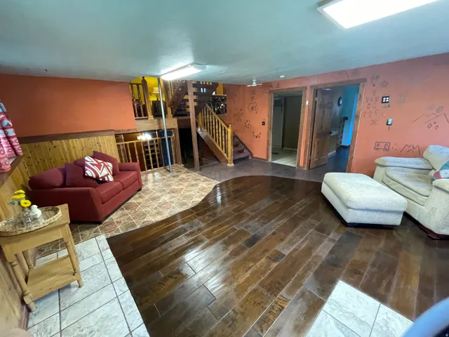 Open-concept living space featuring wood-finish flooring, accent walls, and a staircase with wood railings