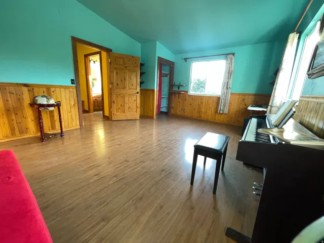 Spacious room featuring wood-finish flooring, natural wood wainscoting, and a window