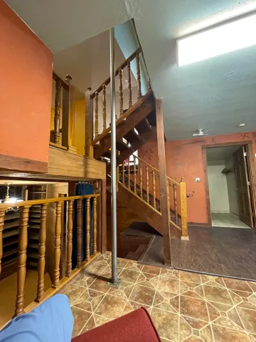 Multi-level interior featuring a wood staircase with turned balusters and a wood-finish railing